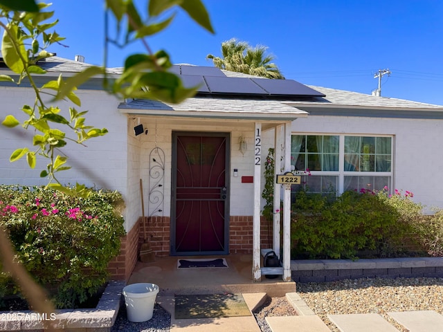 1222 E Almeria Rd, Phoenix, AZ 85006 - view of exterior entry with roof mounted solar panels, brick siding, and roof with shingles
