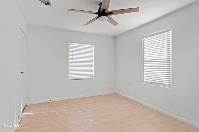 spare room with ceiling fan, a wealth of natural light, and light hardwood / wood-style flooring