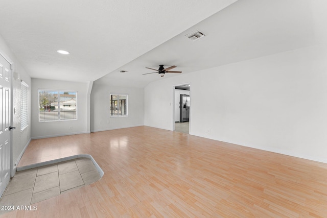 unfurnished living room with light hardwood / wood-style floors, vaulted ceiling, and ceiling fan