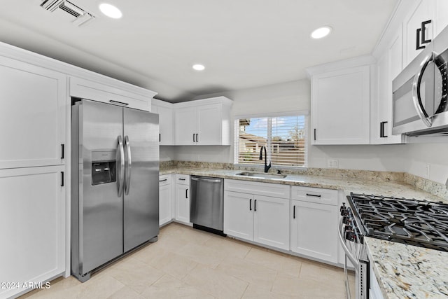 kitchen featuring light stone counters, sink, white cabinets, and stainless steel appliances