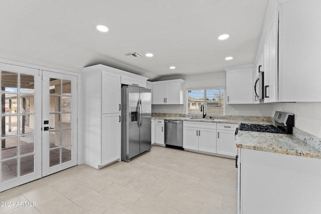 kitchen with white cabinets, french doors, stainless steel appliances, and light stone countertops