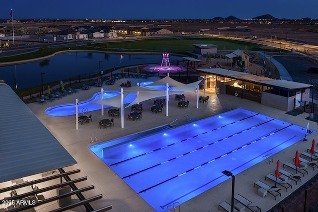 pool at night featuring a patio