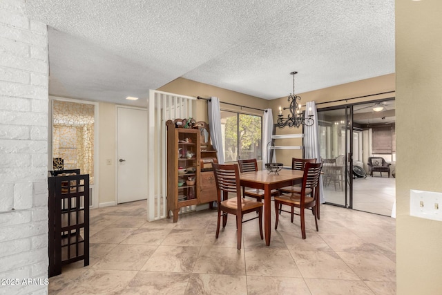 tiled dining room featuring a notable chandelier and a textured ceiling