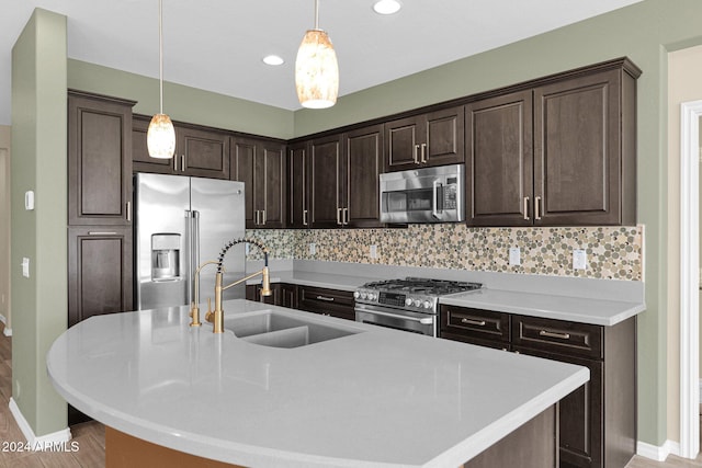 731 E Verde Blvd, Queen Creek, AZ 85140 - kitchen featuring appliances with stainless steel finishes, a sink, dark brown cabinets, decorative light fixtures, and tasteful backsplash