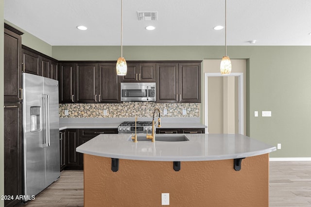 731 E Verde Blvd, Queen Creek, AZ 85140 - kitchen with stainless steel appliances, a sink, light wood-type flooring, a breakfast bar area, and backsplash