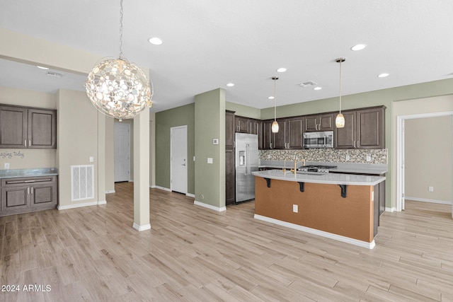 731 E Verde Blvd, Queen Creek, AZ 85140 - kitchen with appliances with stainless steel finishes, light countertops, a kitchen breakfast bar, dark brown cabinetry, and light wood-type flooring