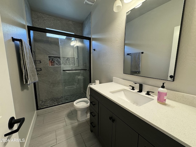 bathroom with vanity, a shower with shower door, and toilet