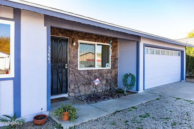 3227 W Villa Rita Dr, Phoenix, AZ 85053 - doorway to property featuring driveway, stone siding, an attached garage, and stucco siding