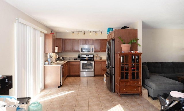 kitchen featuring light tile patterned floors, open floor plan, stainless steel appliances, light countertops, and a sink