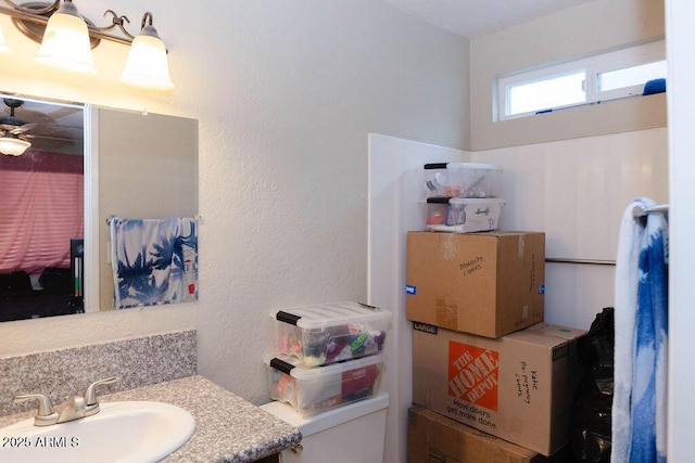 bathroom with a textured wall, a sink, and toilet