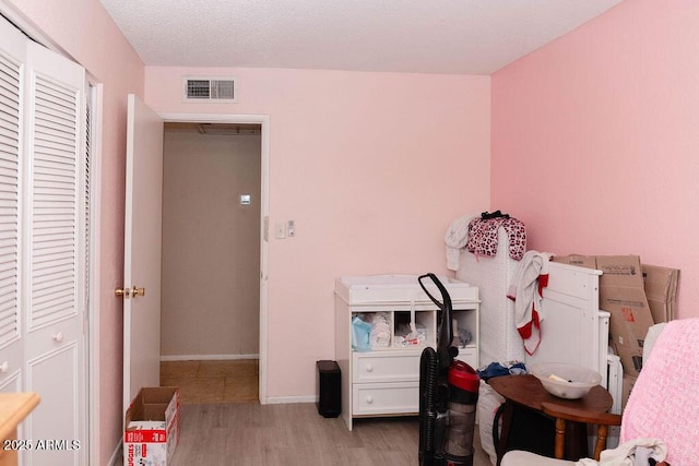 bedroom with baseboards, visible vents, and wood finished floors