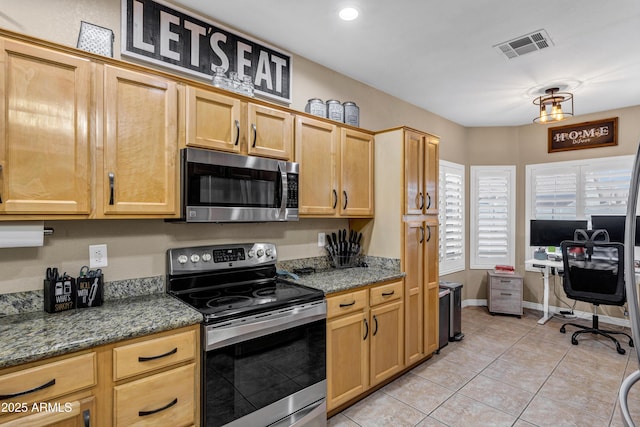 kitchen with light tile patterned flooring, stainless steel appliances, and dark stone counters