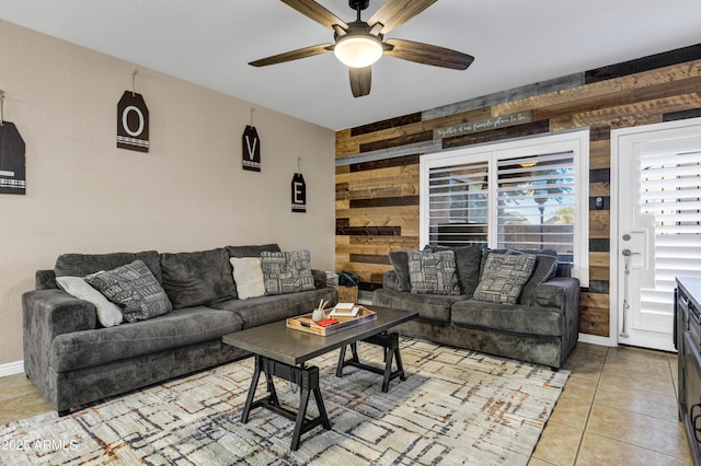 living room with light tile patterned floors, ceiling fan, and wood walls