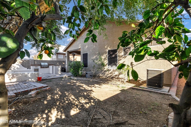 back of property with central AC, exterior kitchen, and a patio