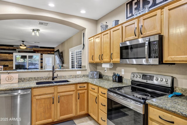 kitchen with light stone countertops, appliances with stainless steel finishes, ceiling fan, sink, and light tile patterned floors