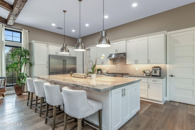 1002 W Rock Springs Cir, Payson, AZ 85541 - kitchen with high quality fridge, under cabinet range hood, backsplash, a large island, and dark wood finished floors