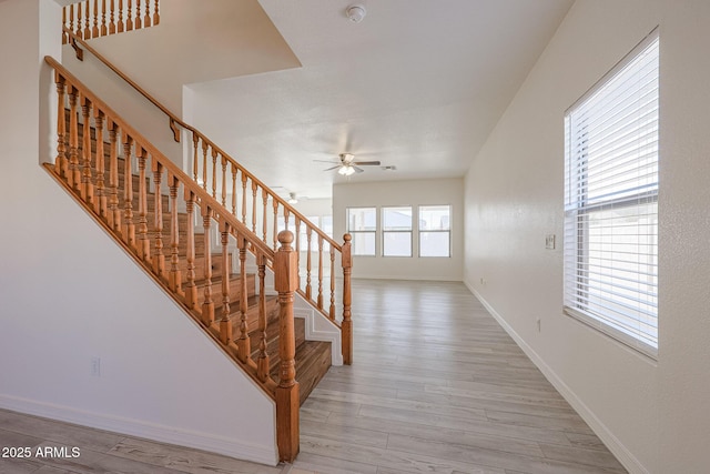 staircase with hardwood / wood-style floors and ceiling fan