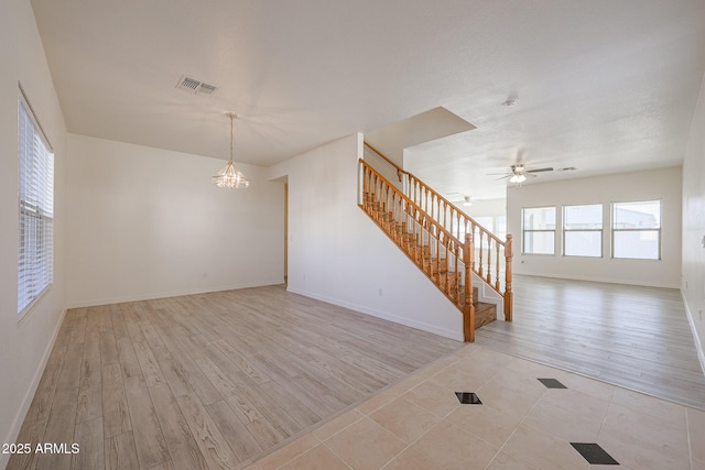 empty room with ceiling fan with notable chandelier and light hardwood / wood-style flooring