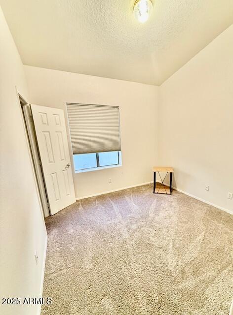 carpeted empty room with baseboards and a textured ceiling