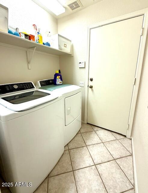 laundry area featuring laundry area, light tile patterned floors, visible vents, and washing machine and clothes dryer