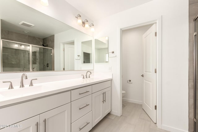 18189 W Hess St, Goodyear, AZ 85338 - full bathroom with double vanity, toilet, a shower stall, and baseboards
