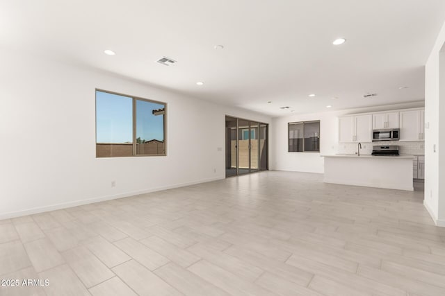 18189 W Hess St, Goodyear, AZ 85338 - unfurnished living room with recessed lighting, a sink, and baseboards