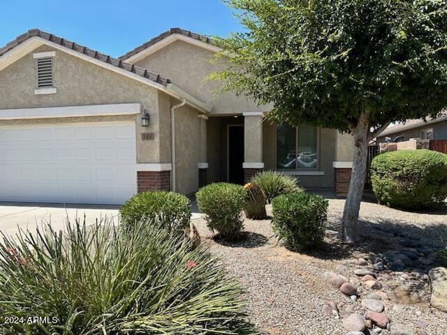 view of front of property with driveway, brick siding, an attached garage, and stucco siding