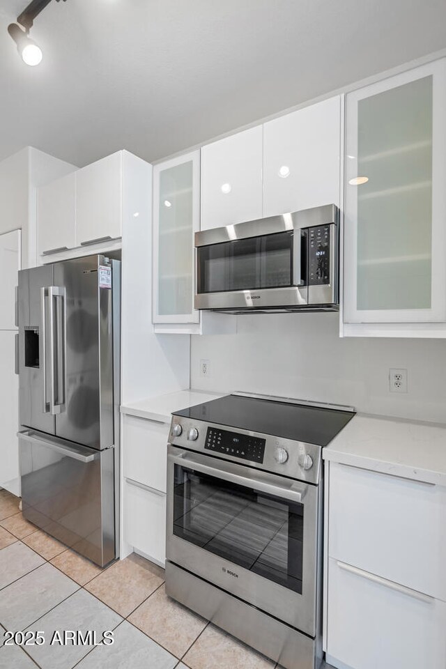 9820 N Central Ave Unit 303, Phoenix, AZ 85020 - kitchen featuring appliances with stainless steel finishes, white cabinetry, light tile patterned floors, and modern cabinets