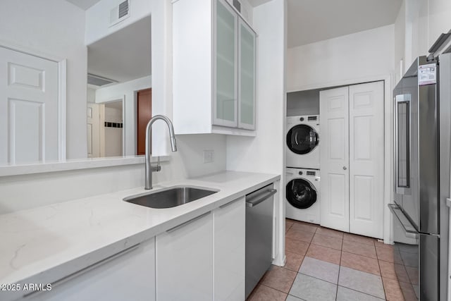 9820 N Central Ave Unit 303, Phoenix, AZ 85020 - kitchen featuring a sink, stacked washing machine and dryer, white cabinetry, and glass insert cabinets