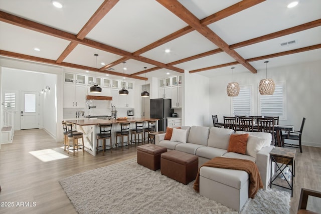 living room with coffered ceiling, light wood-type flooring, and beam ceiling