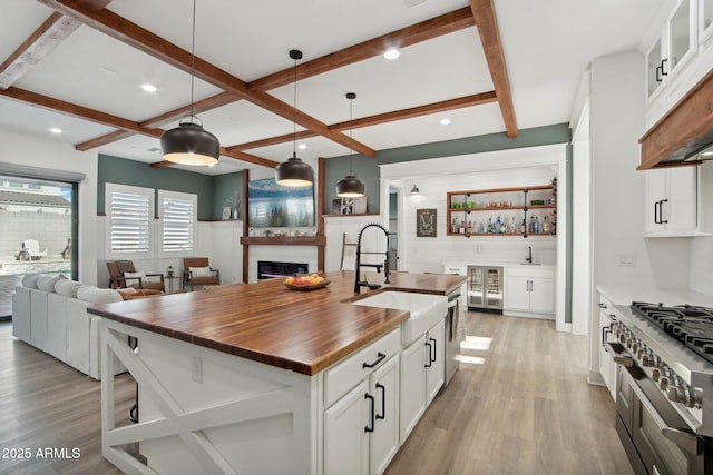 kitchen featuring sink, decorative light fixtures, white cabinets, and a kitchen island with sink