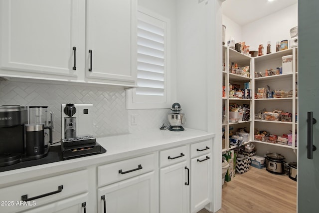 interior space featuring light wood-type flooring, decorative backsplash, and white cabinetry