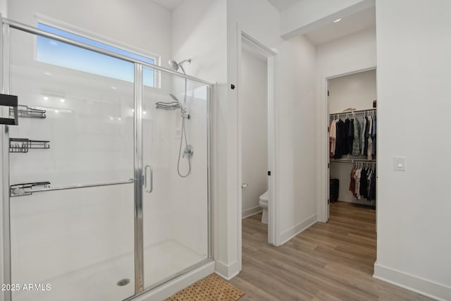 bathroom with a shower with shower door, toilet, and wood-type flooring