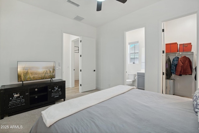 bedroom with a closet, ceiling fan, ensuite bathroom, and a spacious closet