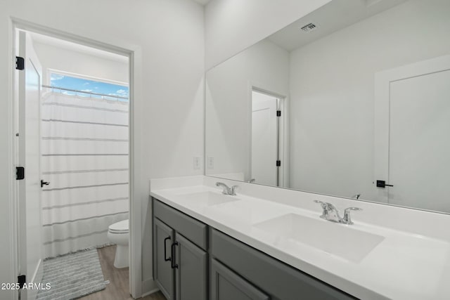 full bathroom with vanity, hardwood / wood-style flooring, shower / bathtub combination with curtain, and toilet