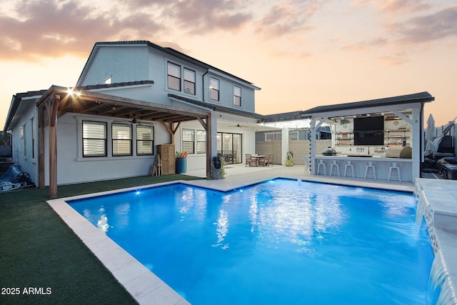 back of property with a patio, pool water feature, area for grilling, ceiling fan, and an outdoor bar