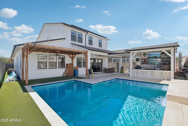 rear view of house featuring ceiling fan, an outdoor bar, exterior kitchen, and a patio