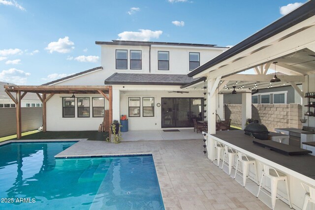 rear view of property featuring area for grilling, a fenced in pool, a patio, and an outdoor bar