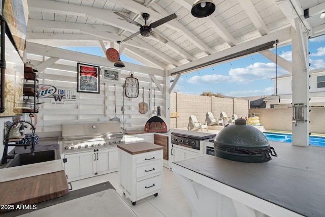 view of patio / terrace with a bar, a grill, an outdoor kitchen, a fenced in pool, and ceiling fan