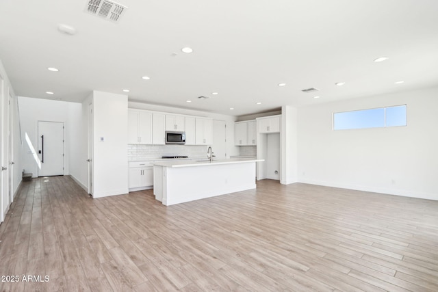 10241 E Ursula Ave, Mesa, AZ 85212 - kitchen with stainless steel microwave, open floor plan, white cabinets, light countertops, and a center island with sink