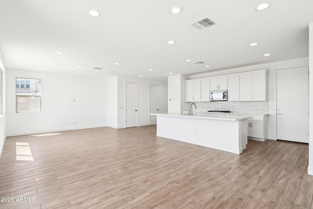 10241 E Ursula Ave, Mesa, AZ 85212 - kitchen with stainless steel microwave, a kitchen island with sink, a sink, recessed lighting, and light wood finished floors
