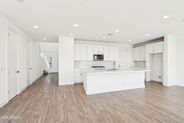 10241 E Ursula Ave, Mesa, AZ 85212 - kitchen featuring stainless steel microwave, a sink, light wood-style floors, white cabinets, and light countertops