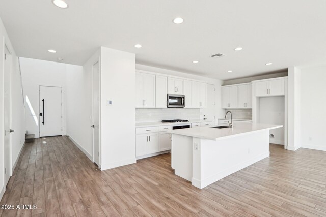 10241 E Ursula Ave, Mesa, AZ 85212 - kitchen with appliances with stainless steel finishes, backsplash, white cabinets, light wood finished floors, and light countertops