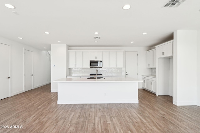 10241 E Ursula Ave, Mesa, AZ 85212 - kitchen with stainless steel microwave, a sink, backsplash, light wood finished floors, and recessed lighting