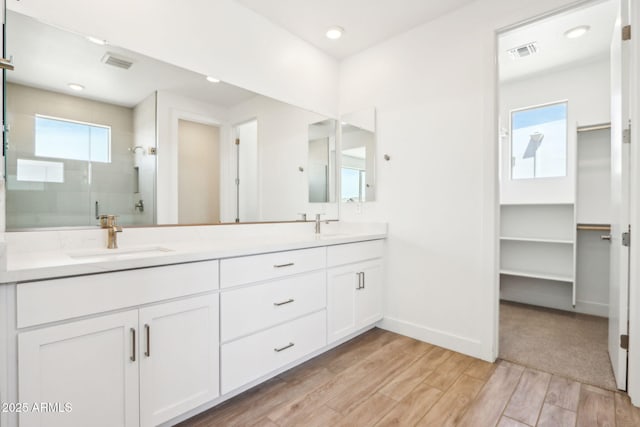 10241 E Ursula Ave, Mesa, AZ 85212 - bathroom featuring double vanity, a stall shower, wood finished floors, and a spacious closet