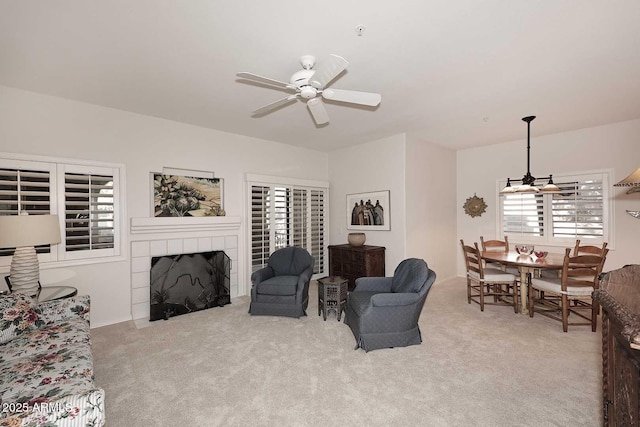 carpeted living room with a tile fireplace and ceiling fan