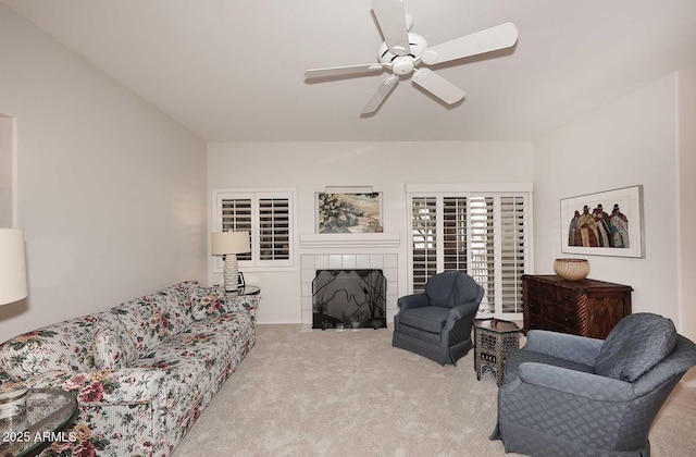 living room featuring a tile fireplace, light carpet, and ceiling fan