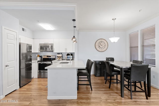 kitchen with decorative light fixtures, sink, white cabinetry, and appliances with stainless steel finishes