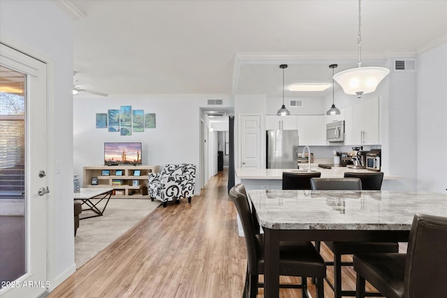 dining area with ceiling fan, crown molding, and light hardwood / wood-style floors