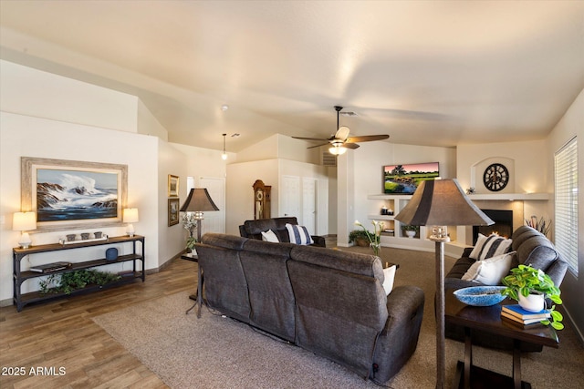 3658 E Pony Track Ln, San Tan Valley, AZ 85140 - living room with lofted ceiling, ceiling fan, wood finished floors, a lit fireplace, and baseboards